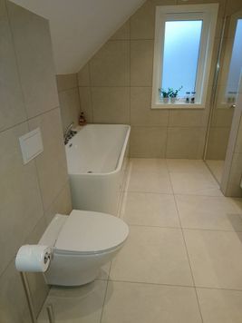 Badekar og toalett på bad med store fliser